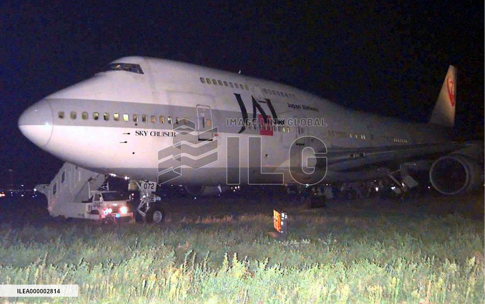 JAL jumbo gets stuck in grass at Kansai airport