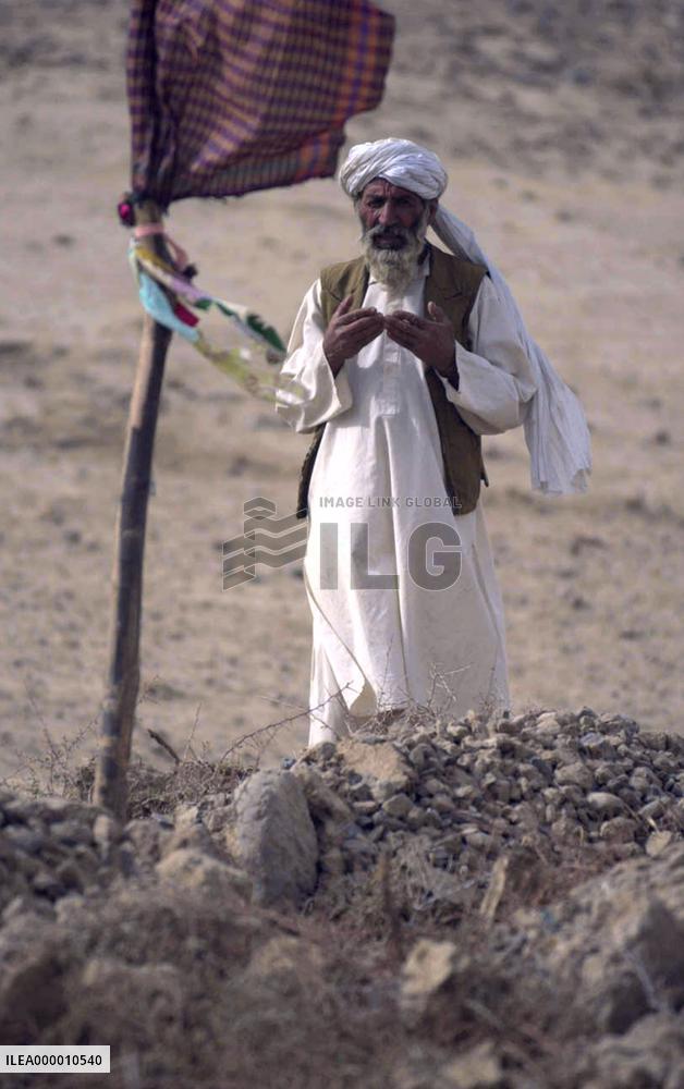 An elderly Afghan man prays Nov. 1 in front of tombs