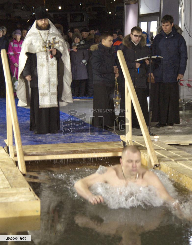 Orthodox Church priest prays as follower soaks in icy water