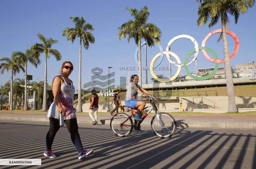 Woman walks by Olympic rings in Rio de Janeiro park