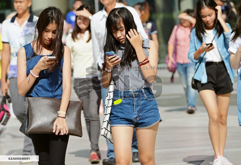 Thai women use smartphones while walking in Bangkok