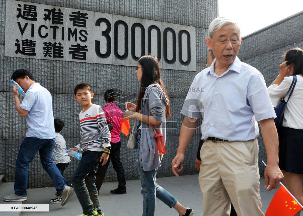Visitors walk by wall display at Nanjing Massacre Museum