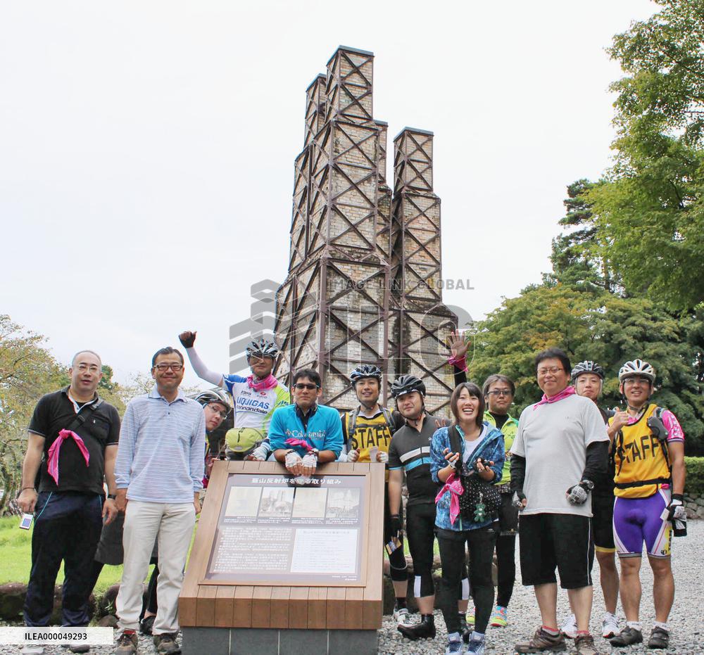 Participants in cycling tour pose before World Heritage furnace