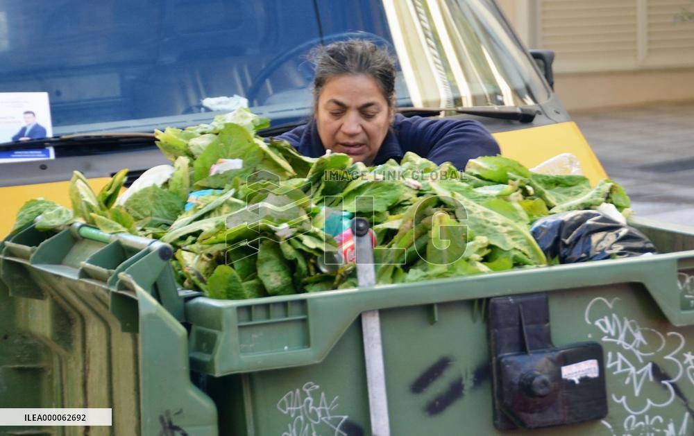 Athens woman sorts out vegetables in trash bin