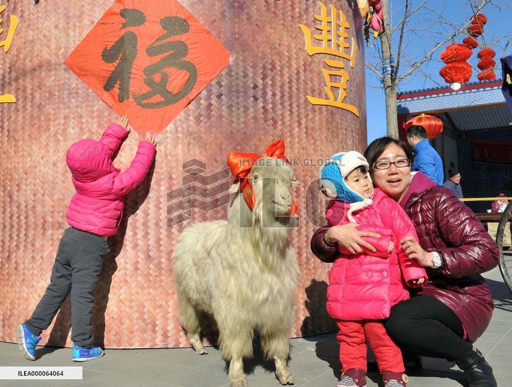 Mother, daughter pose by stuffed sheep in Beijing park