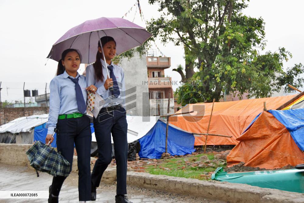 Students walk past quake-hit people's tents in Nepal