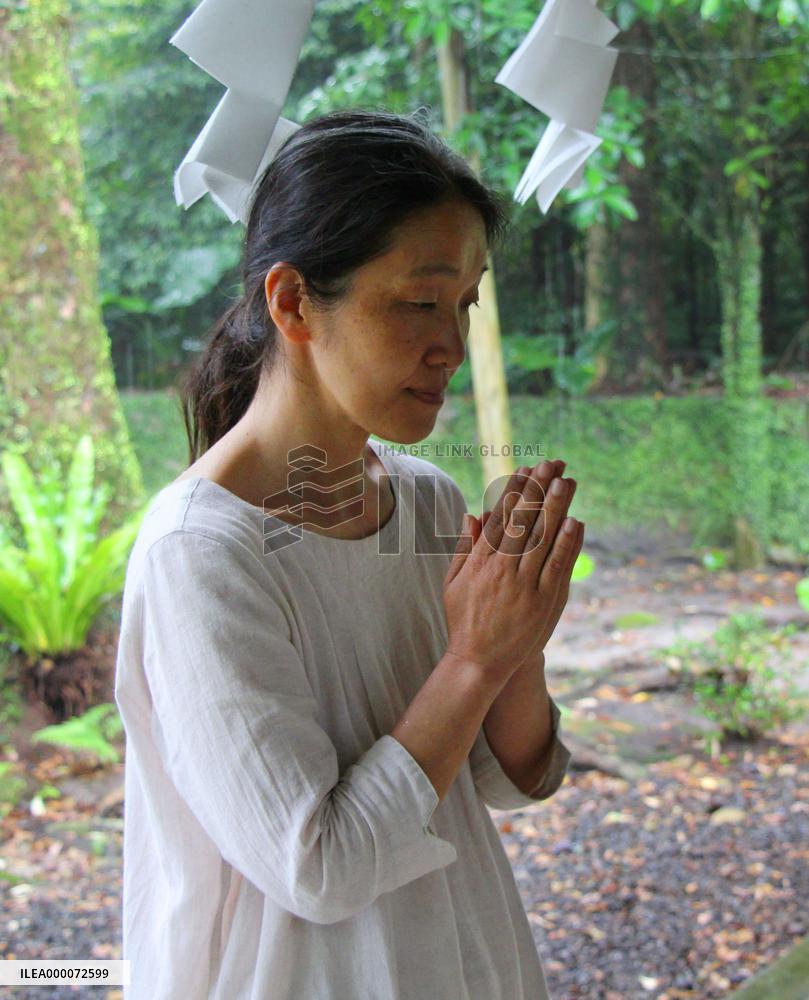 Female Shinto priest prays to calm volcano