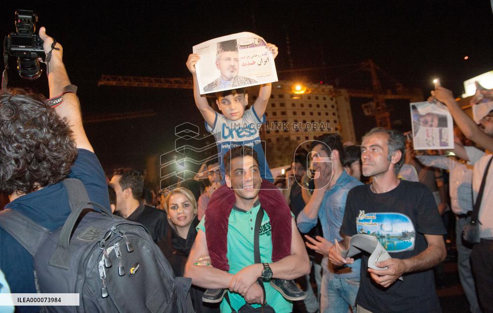Boy holds paper with Iranian FM's photo after nuclear agreement