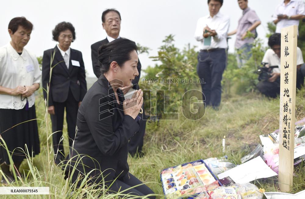 Japanese woman prays in front of grave marker in N. Korea