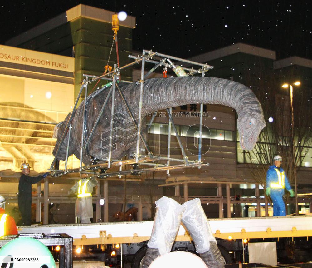 Life-size dinosaur model lifted by crane