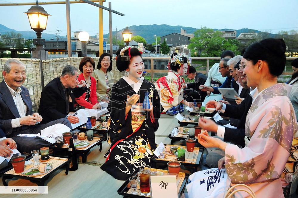 Visitors enjoy cuisine on riverside terrace in Kyoto