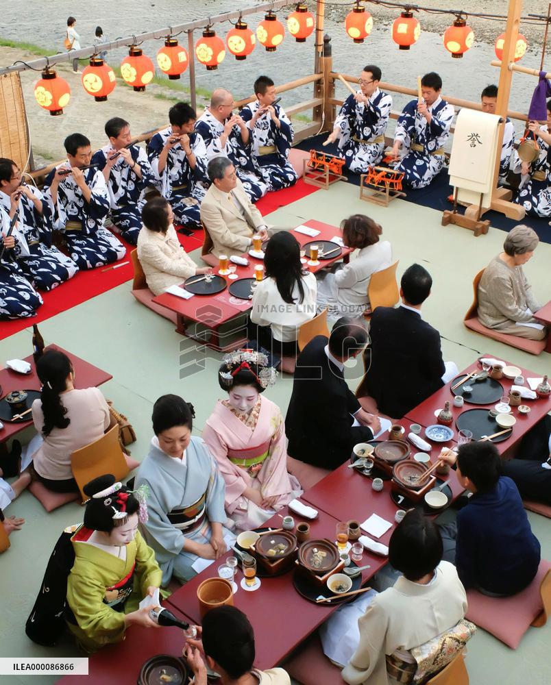Visitors enjoy cuisine on riverside terrace in Kyoto