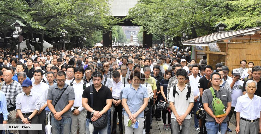 People stand in silence in front of Yasukuni Shrine