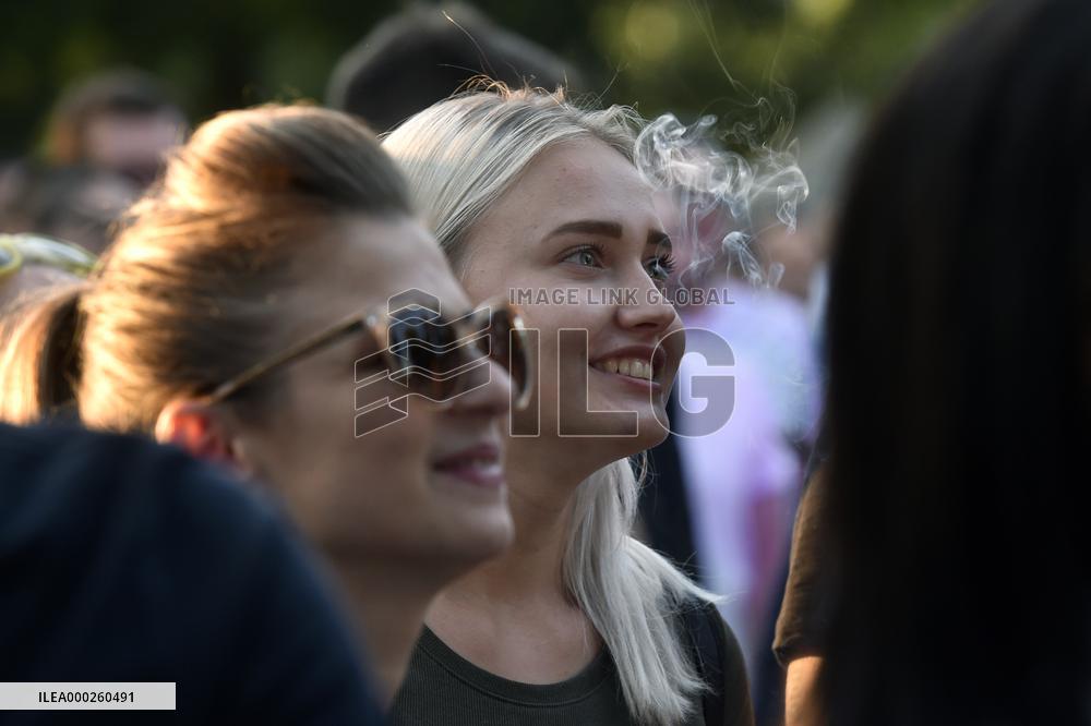 spectators watch a performance, woman, women, girl, girls, smile, smoke, sunglasses