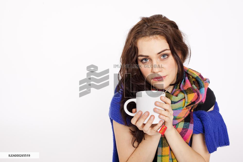 A beautiful young woman, lady, girl, cold, runny nose, headache, cup of tea, scarf, hot drink