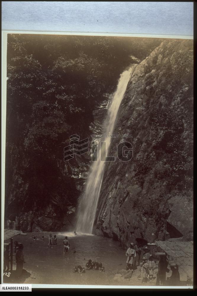 Children bathing in the basin of a waterfall and onlookers