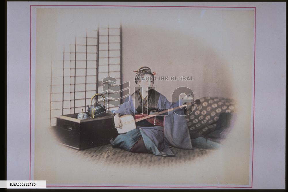 A woman playing the shamisen,and a box brazier