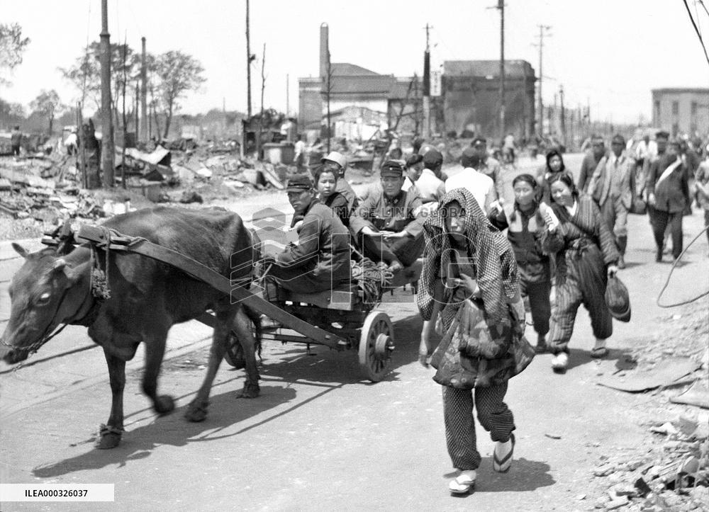 Civilians riding oxcart, walking through Tokyo during wartime