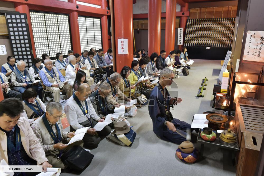 Bus tour participants chant Buddhist sutra at temple