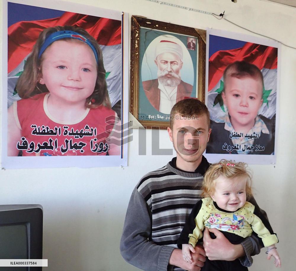 Syrian man holds sister in front of photos of kin killed in war