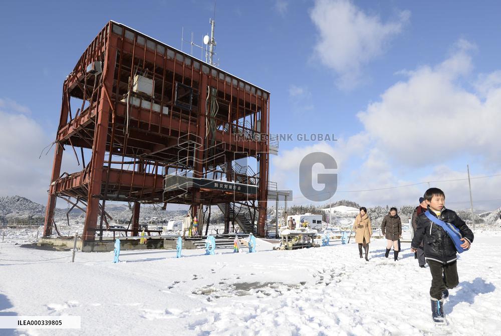 People walk by frame of building damaged by 2011 disaster