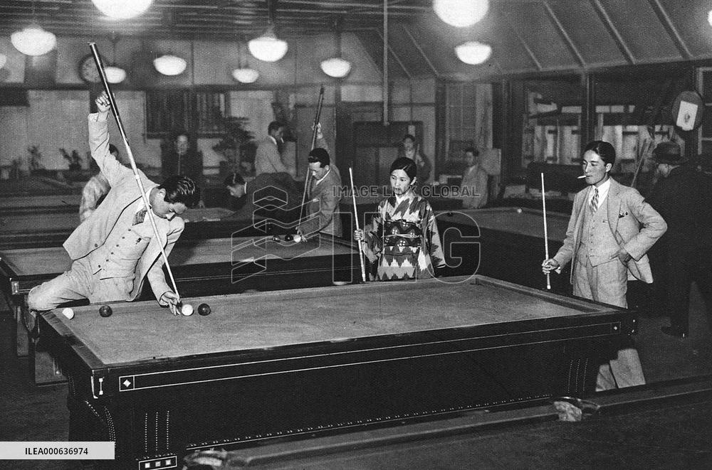 Three young Japanese people play billiards