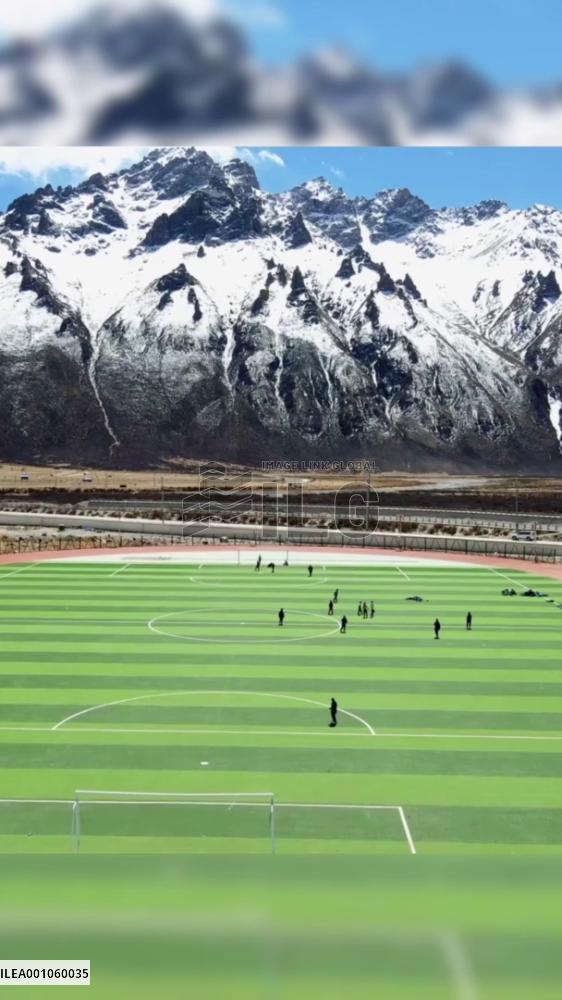Picturesque football field at foot of snow-capped mountains in Tibet, China