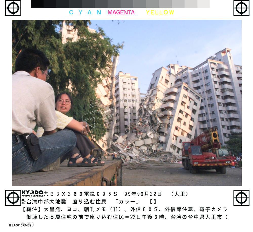 Residents sit resigned in front of collapsed apartments