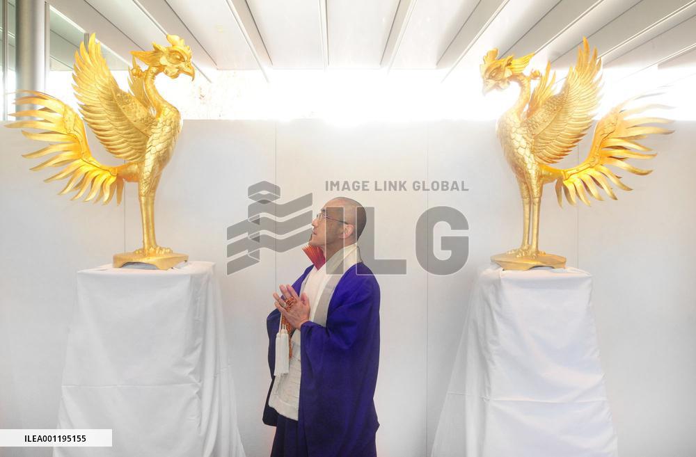 Monk watches golden phoenix statue at Kyoto temple