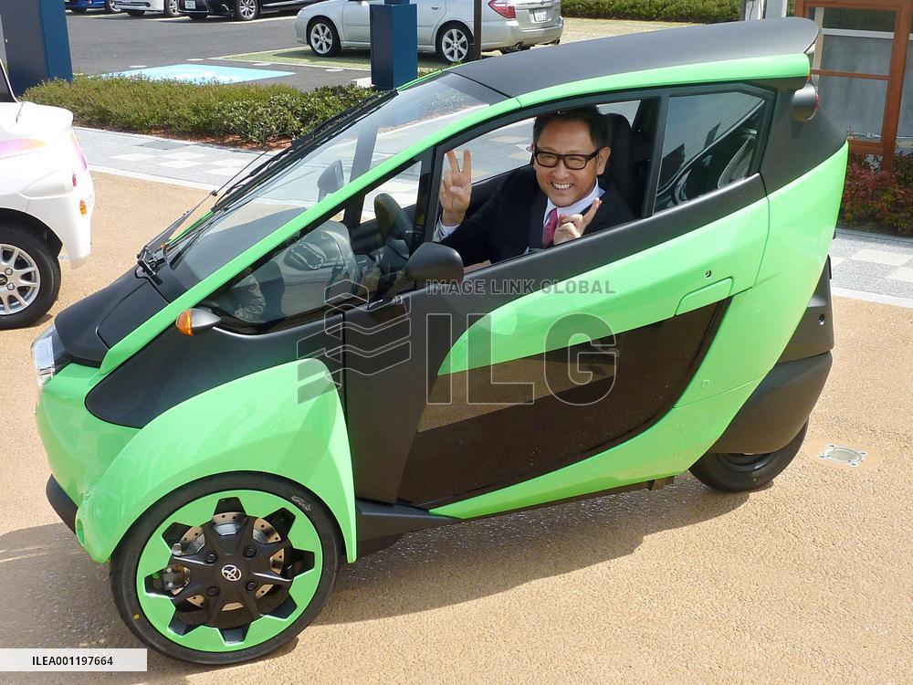Toyota Motor chief gives victory sign in small electric vehicle