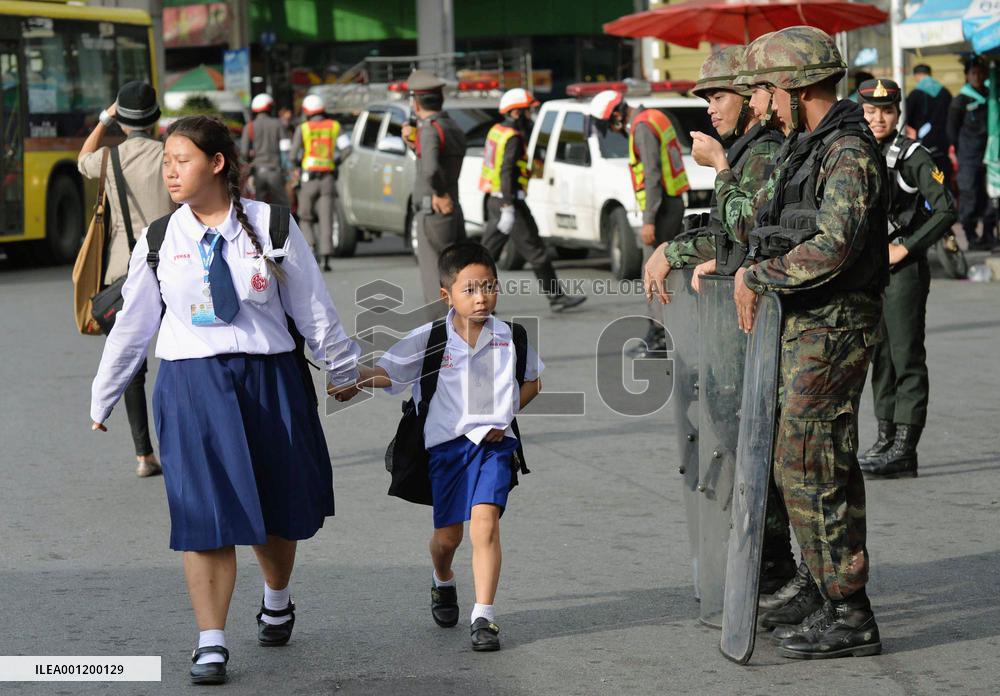 Thai schoolchildren walk past soldiers standing guard