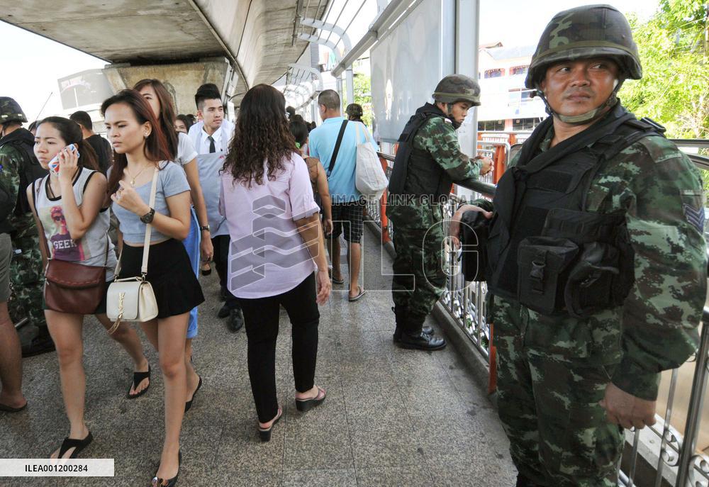 Citizens walk past solders standing guard in Bangkok