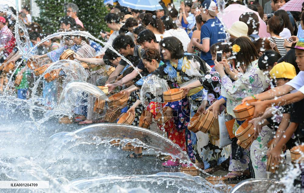 People splash water on car-free street in Tokyo's Ginza