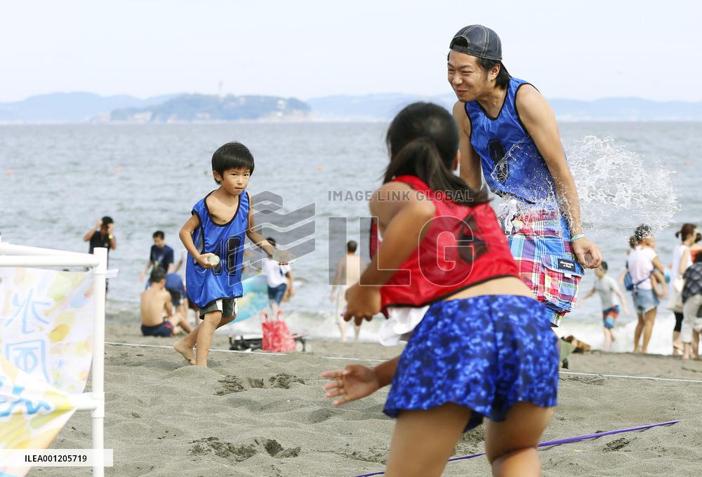 Young people enjoy water balloon fight on Japan beach