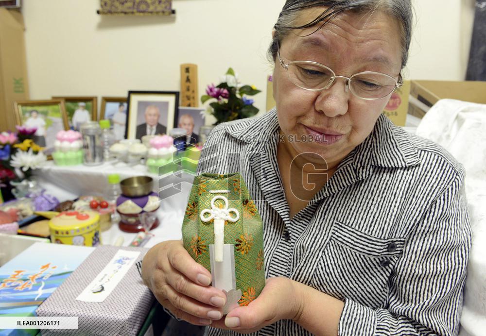 Woman holds urn with soil from home in memory of husband