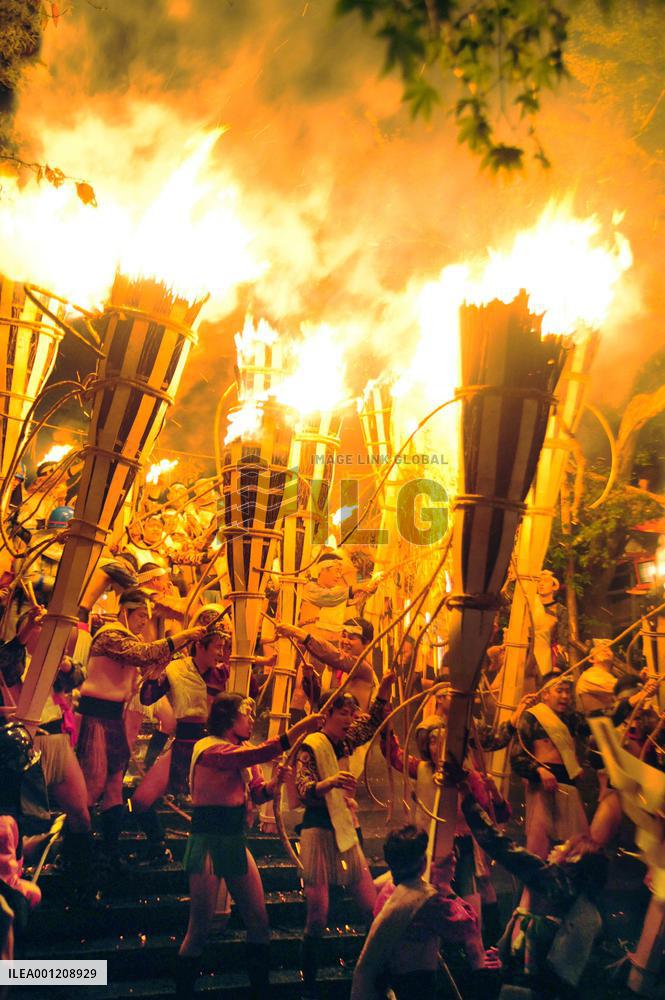 Young men hold up huge torches at Kyoto fire festival