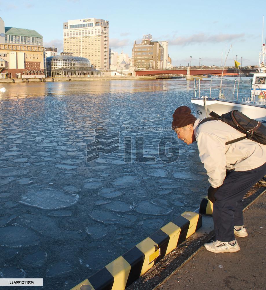 Man looks at pancake ice on Kushiro River in Hokkaido