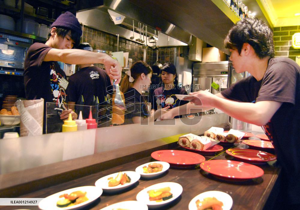 Employees prepare hot dogs in Nipponham travel cafe in Osaka