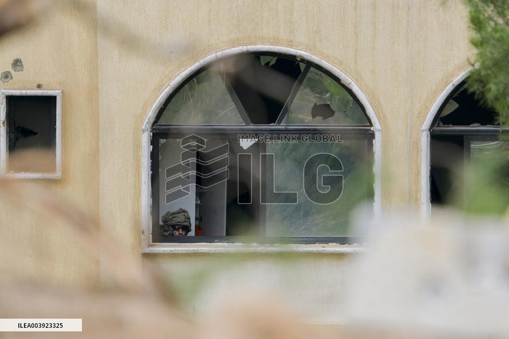 Israeli Soldiers Gather Behind Rubble In A Southern Lebanese Village