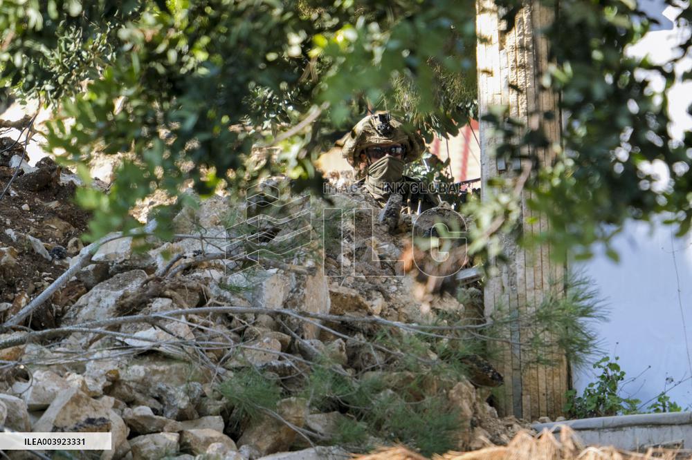 Israeli Soldiers Gather Behind Rubble In A Southern Lebanese Village