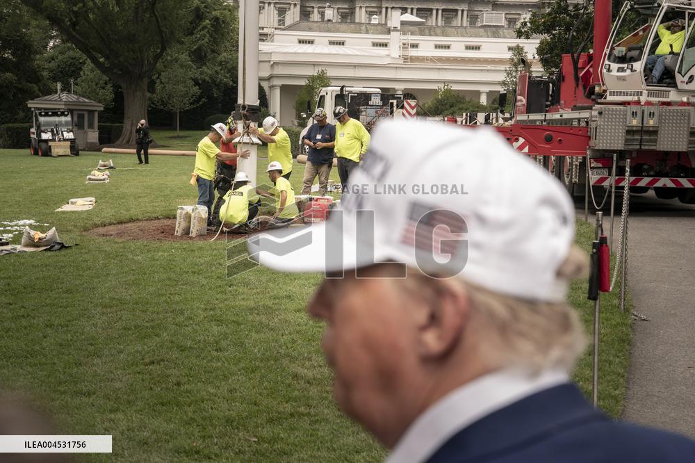 President Trump speaks to the press while workers instals a new flag pole on South Lawn