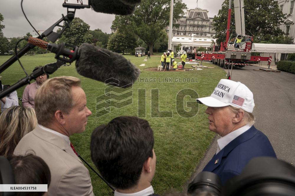President Trump speaks to the press while workers instals a new flag pole on South Lawn