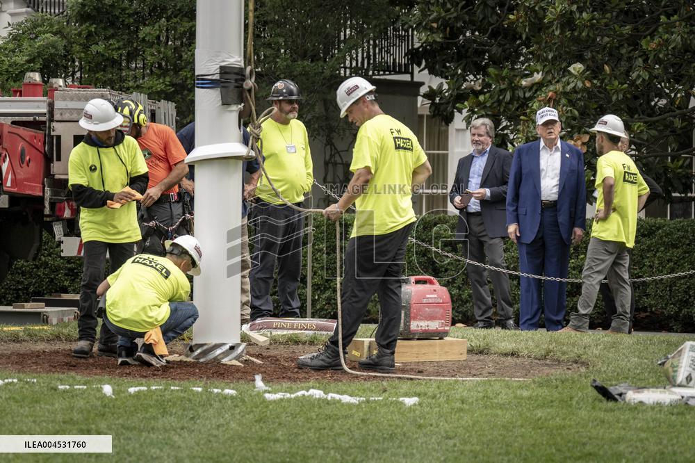 President Trump speaks to the press while workers install a new flag pole on South Lawn