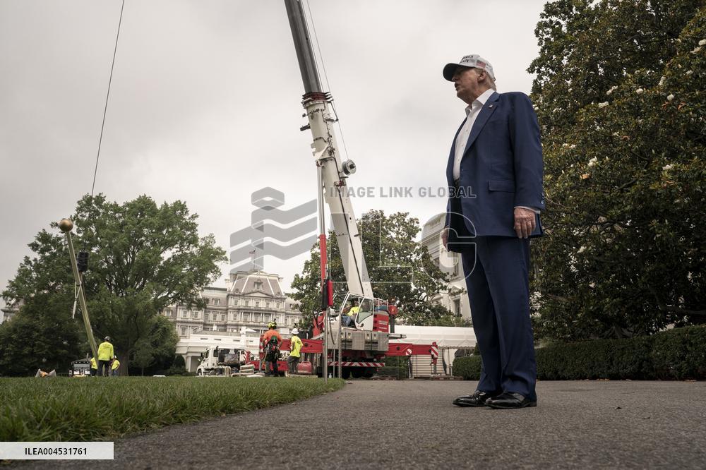 President Trump speaks to the press while workers instals a new flag pole on South Lawn