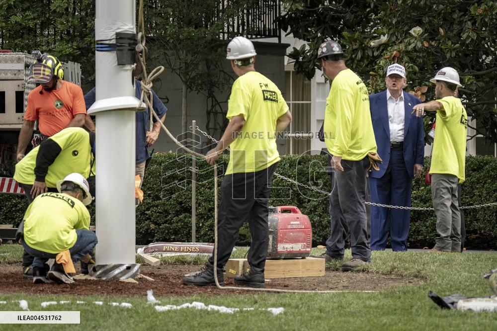 President Trump speaks to the press while workers install a new flag pole on South Lawn