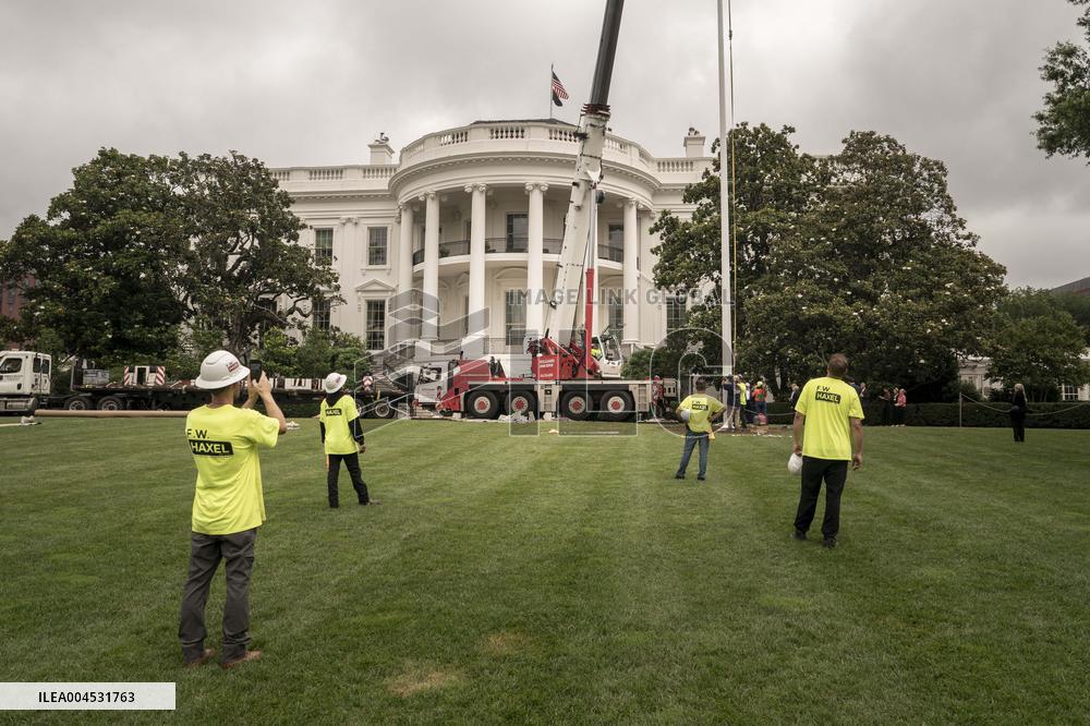 President Trump speaks to the press while workers install a new flag pole on South Lawn