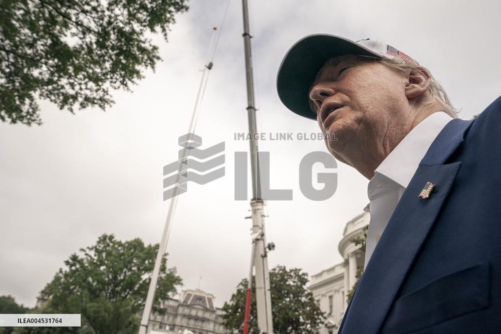 President Trump speaks to the press while workers installs a new flag pole on South Lawn