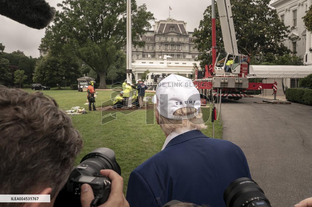 President Trump speaks to the press while workers installs a new flag pole on South Lawn