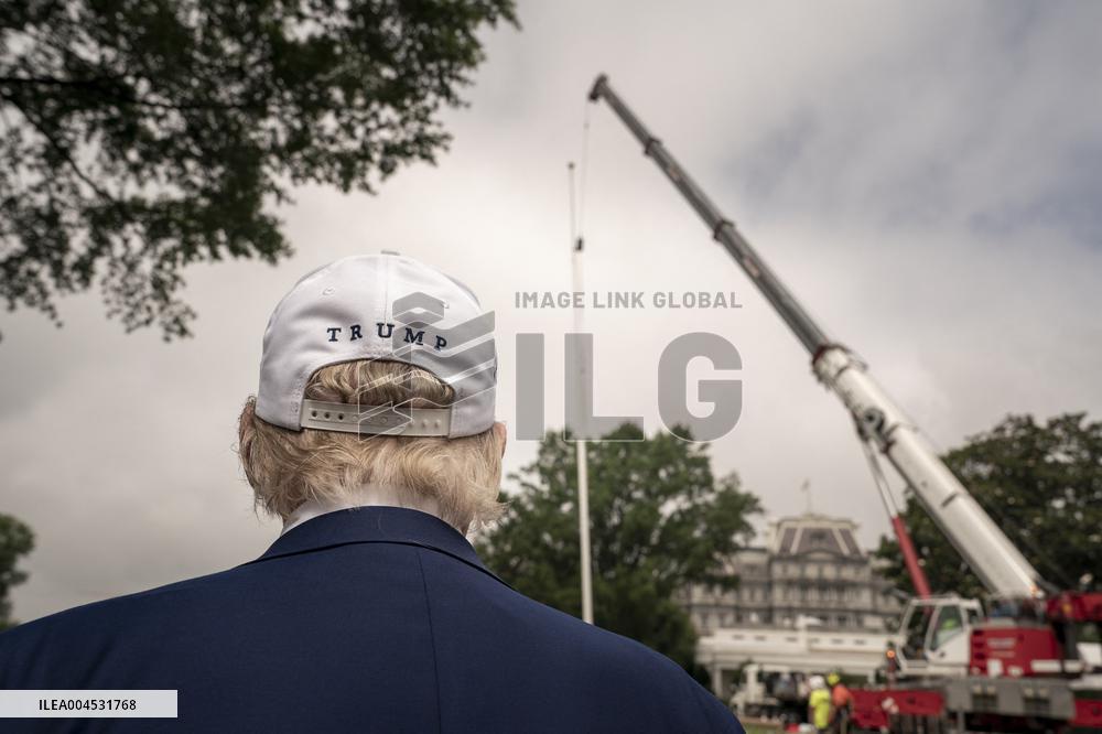 President Trump speaks to the press while workers installs a new flag pole on South Lawn