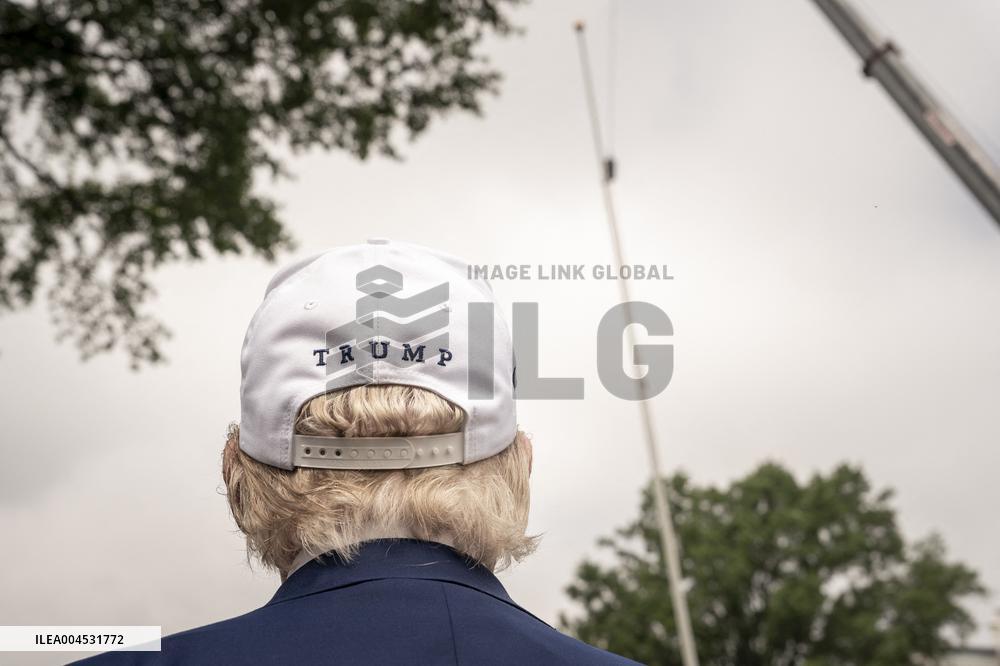 President Trump speaks to the press while workers installs a new flag pole on South Lawn